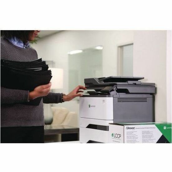 Office worker operating Lexmark printer with stack of documents for printing