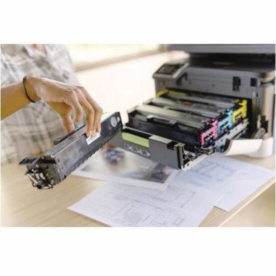 Close-up of hands installing toner cartridge in Lexmark printer with technical documents