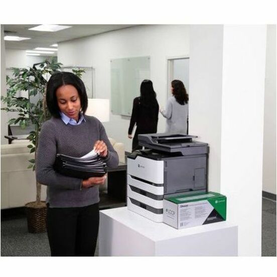 Office worker reviewing printed documents next to a Lexmark printer with toner supplies