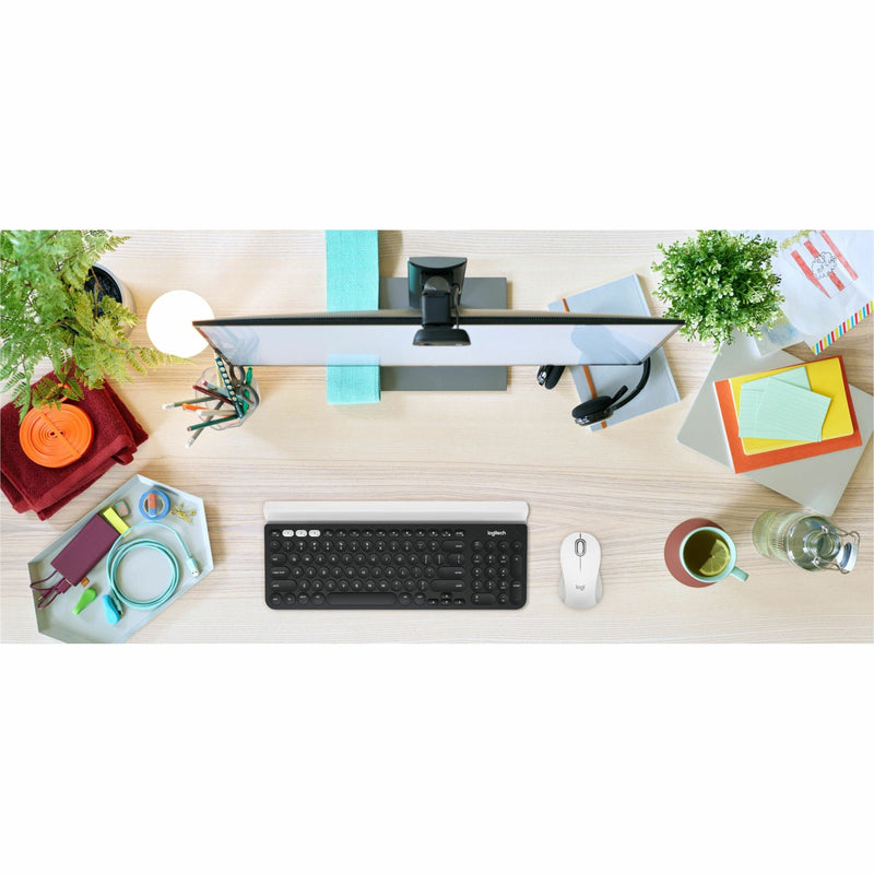 Overhead view of organized desk setup featuring Logitech M550 mouse with keyboard, monitor, and office accessories