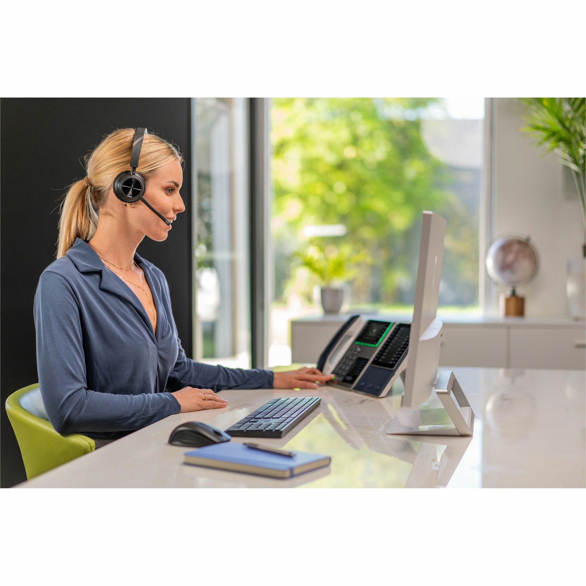 Professional using Poly Voyager headset with multiple devices in bright office space-alternate-image5