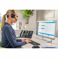 Professional using Poly Voyager headset with business applications and desk phone-alternate-image7