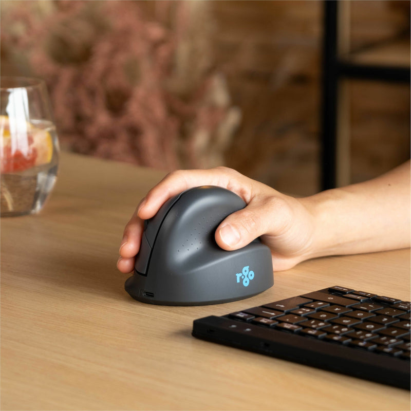 Close-up of hand using R-Go ergonomic mouse next to keyboard on wooden desk