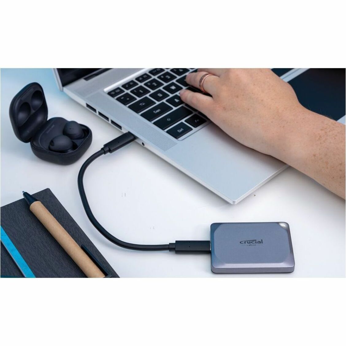 Crucial X9 Pro SSD connected to laptop with wireless earbuds nearby-alternate-image3