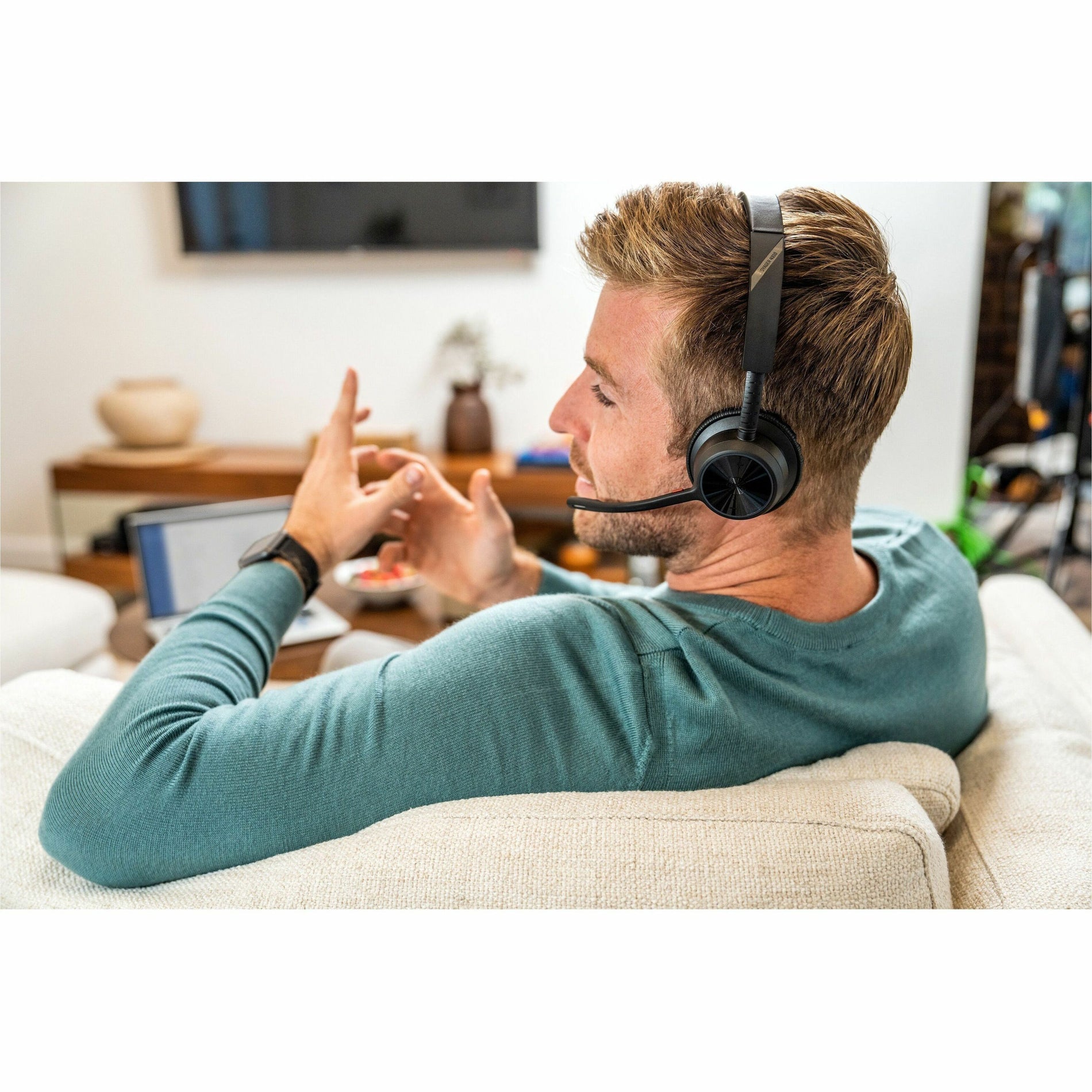 Side view of person relaxing on couch while wearing Poly Voyager headset during work-alternate-image8