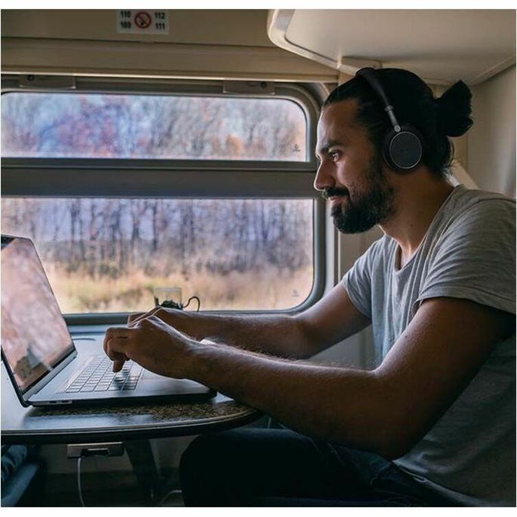 Person using Yealink BH76 Plus while working on laptop during travel-alternate-image11