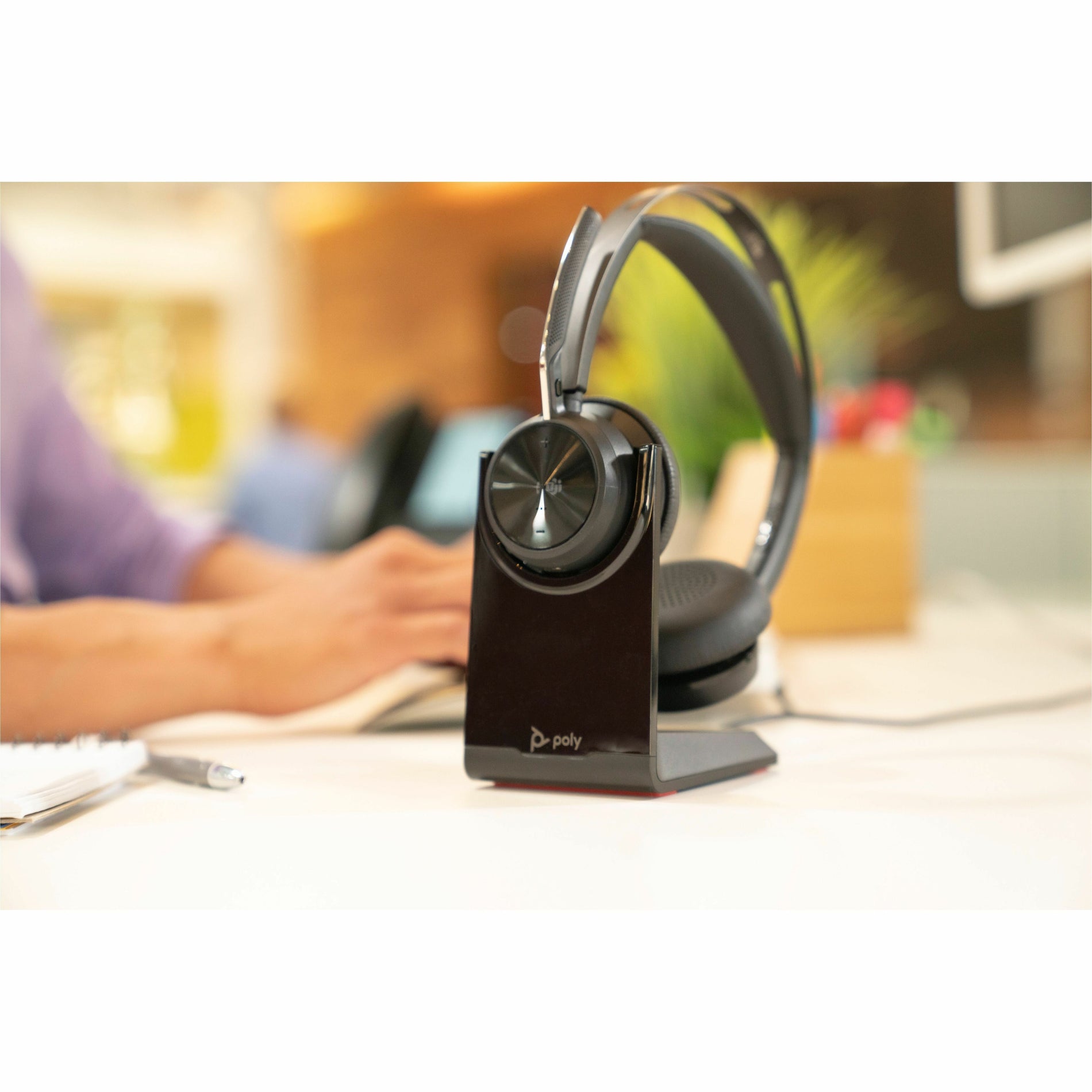 Poly Voyager Focus 2 headset on charging stand in office environment-alternate-image3