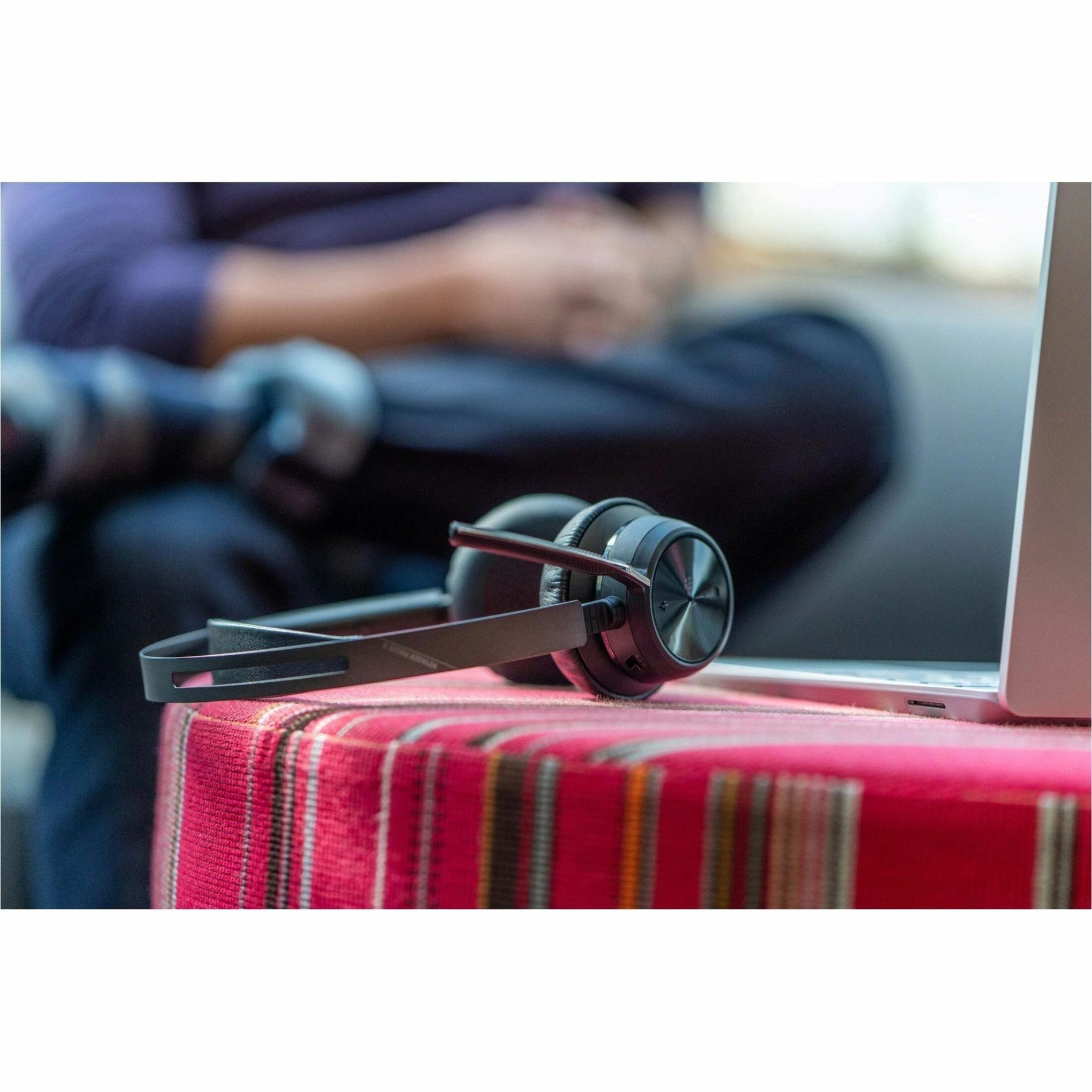 Lifestyle image of Poly Voyager Focus 2 headset next to laptop in work environment-alternate-image4