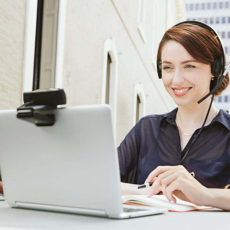 Professional using Logitech C930e webcam for video conferencing in office setting