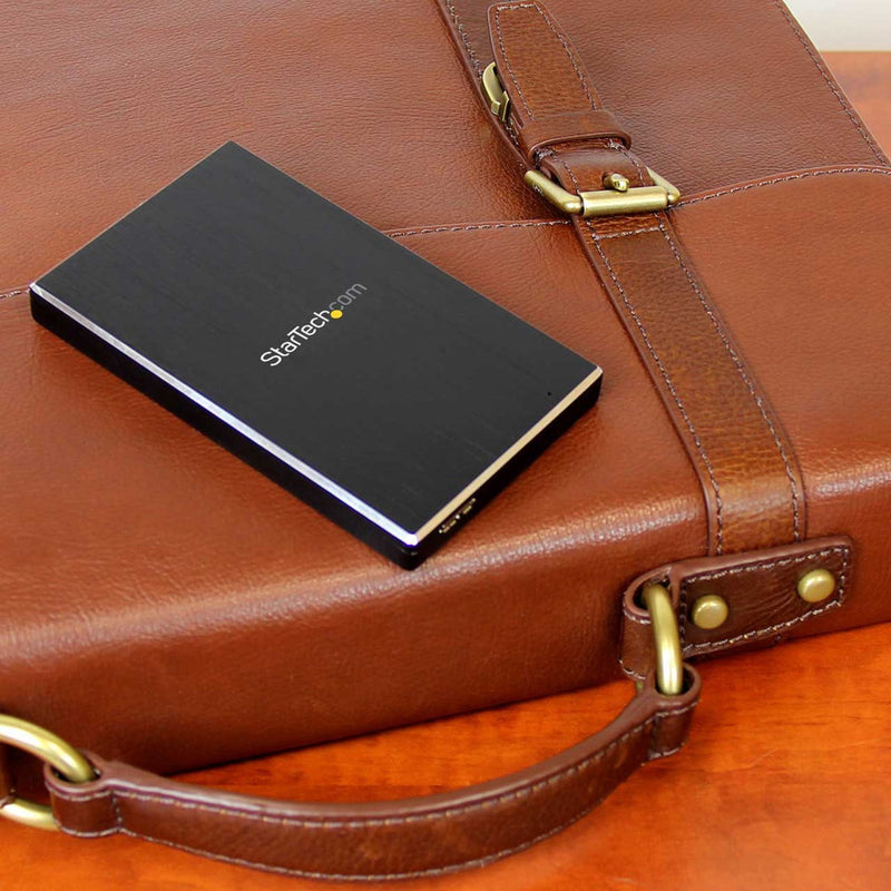 StarTech.com drive enclosure placed on brown leather briefcase showing portable design