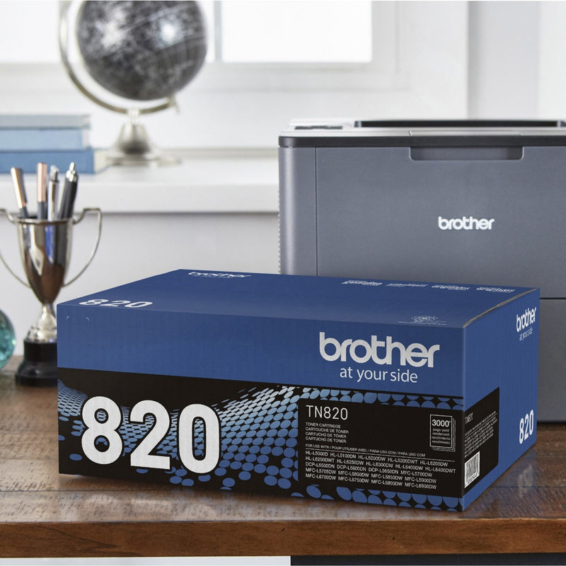 Brother TN820 toner cartridge box next to compatible Brother printer in office setting