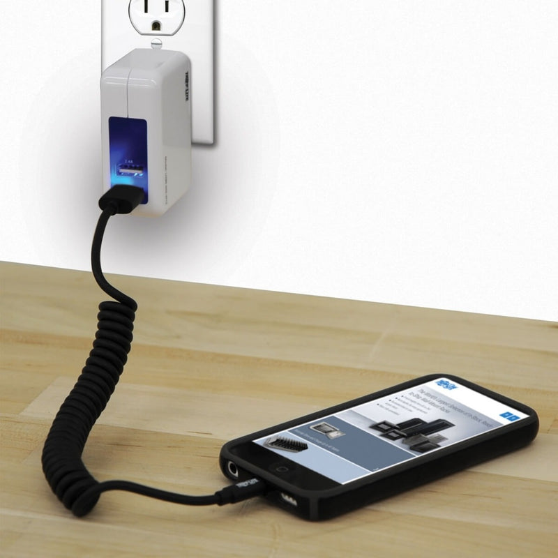 Coiled Lightning cable in use charging iPhone from wall adapter showing practical application