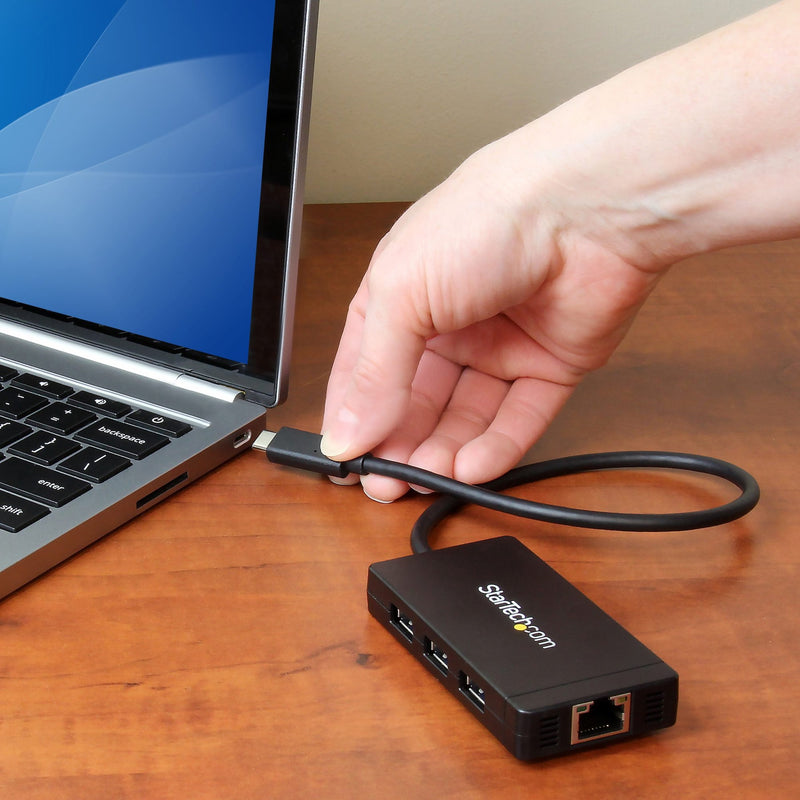 StarTech.com USB-C hub being connected to a laptop on wooden desk