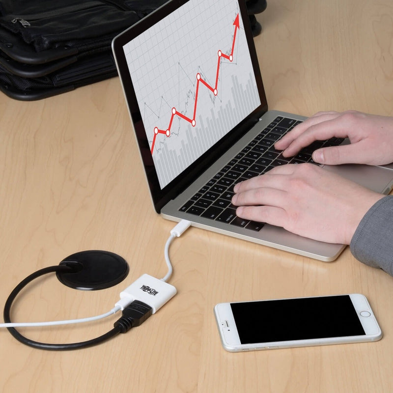 Close-up of laptop displaying financial data connected via adapter