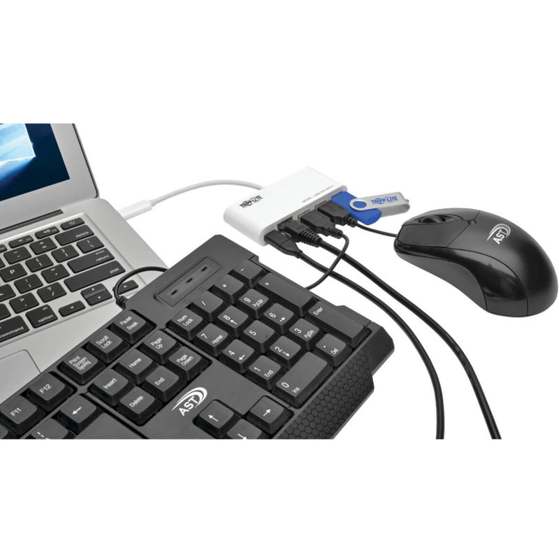 Tripp Lite USB-C hub connected to laptop with keyboard, mouse, and USB drive showing practical usage