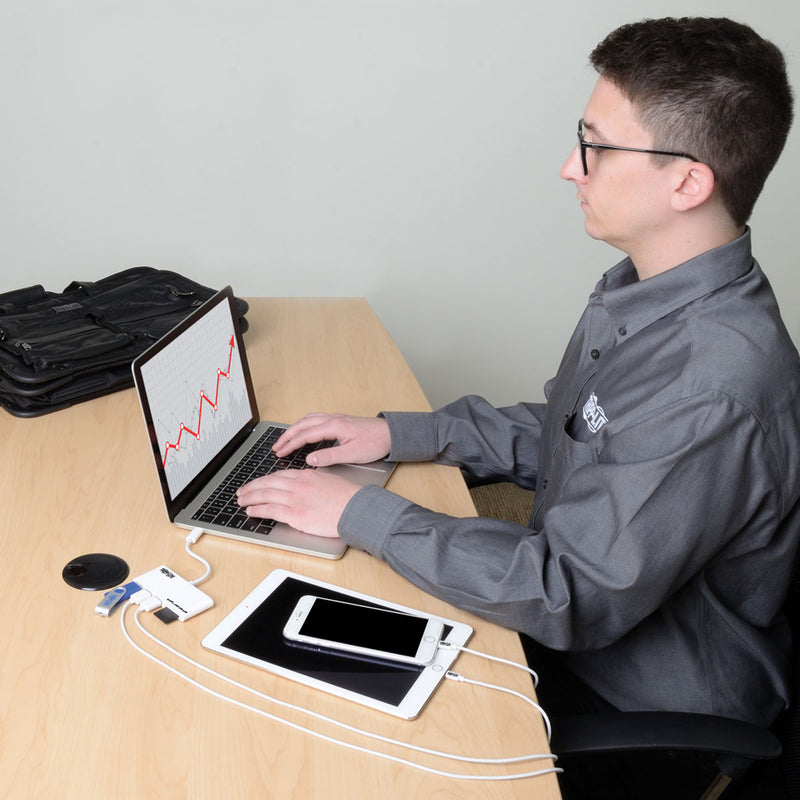 Person using laptop with USB hub connected to multiple devices on desk