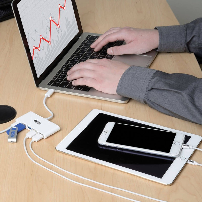 Close-up of USB hub connected to laptop with tablet and phone charging