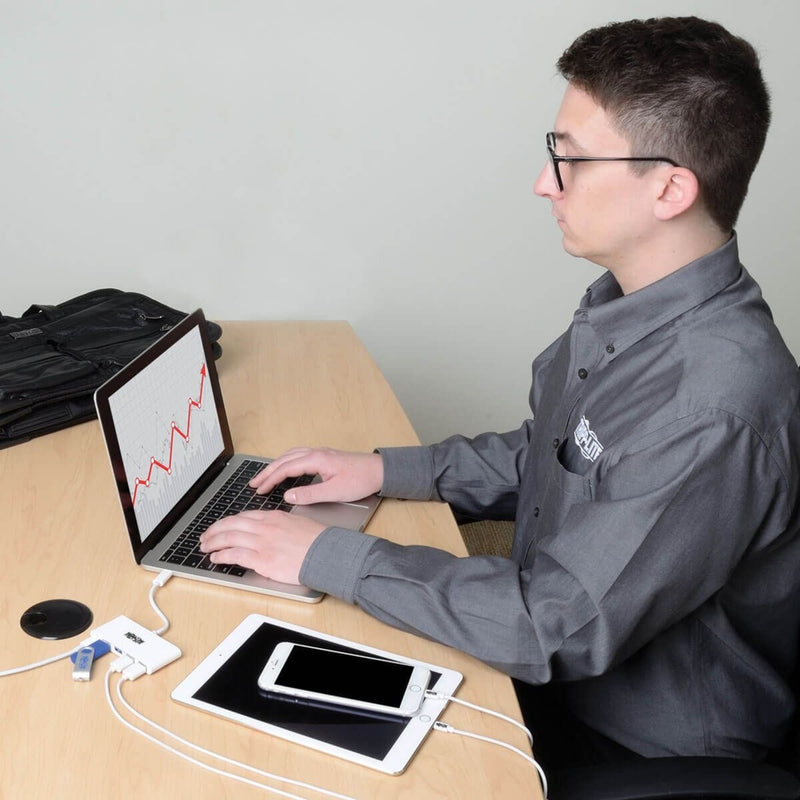 Professional using laptop with USB hub connected to multiple devices in office setting