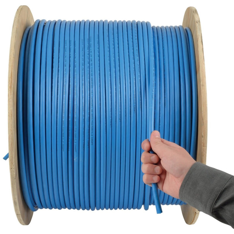 Hand pulling blue Cat6a cable from wooden spool demonstrating ease of use