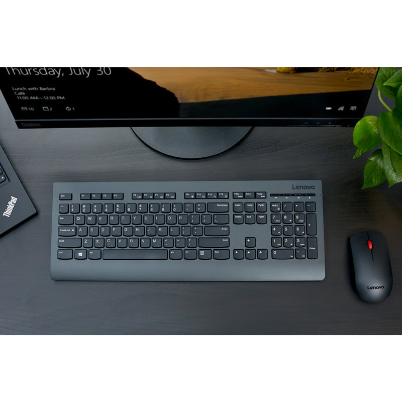 Overhead view of Lenovo wireless keyboard and mouse on dark desk surface with monitor in background