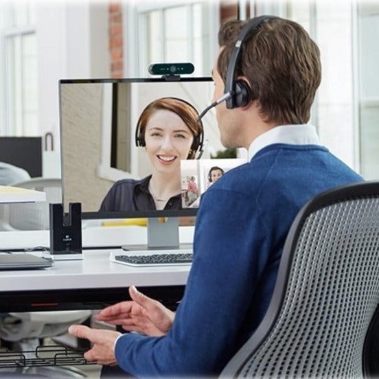 Professional using Logitech BRIO webcam for video conferencing in office setting