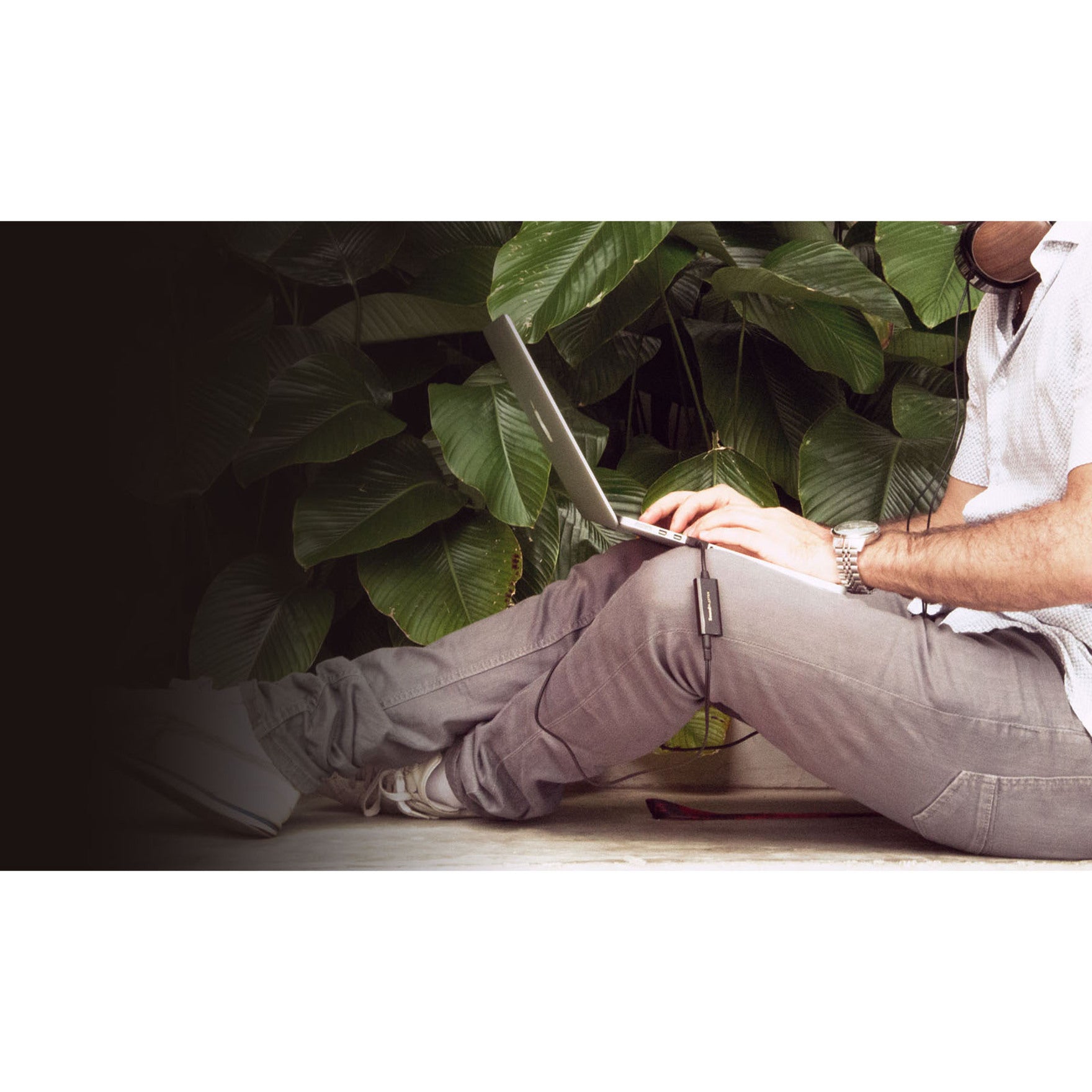 Person using Sound Blaster PLAY! 3 with laptop in casual setting with plants-alternate-image6