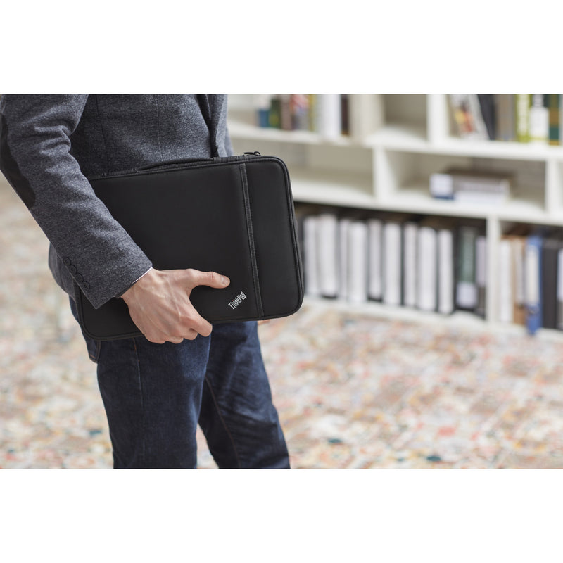 Person in business attire holding ThinkPad sleeve in office setting