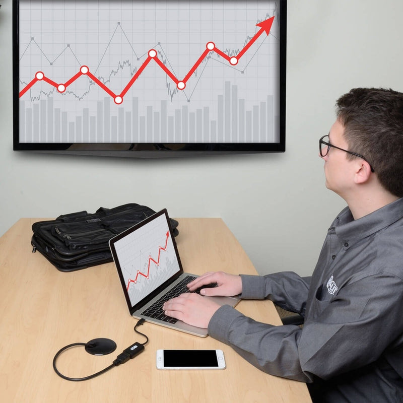 Person using laptop connected to large monitor displaying financial charts