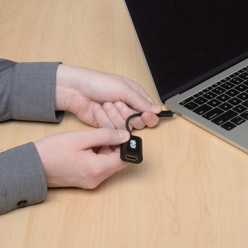 Close-up of hands connecting USB-C adapter to laptop