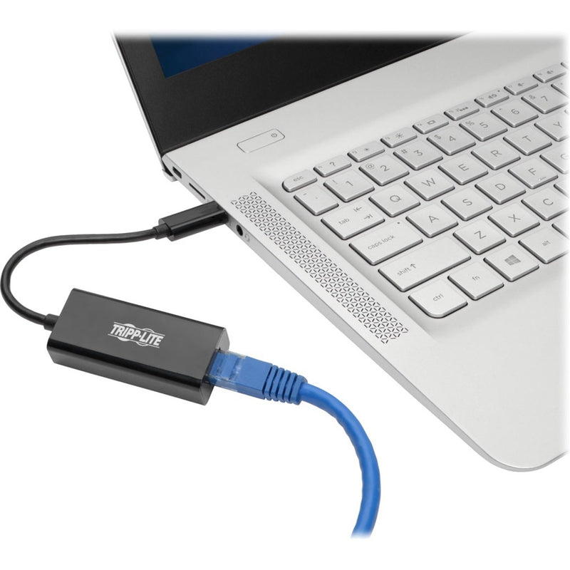 Tripp Lite USB-C network adapter connected to a modern laptop with Ethernet cable attached