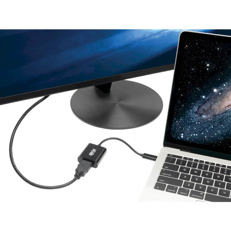 Tripp Lite USB-C to HDMI adapter connected between a MacBook and monitor showing practical usage