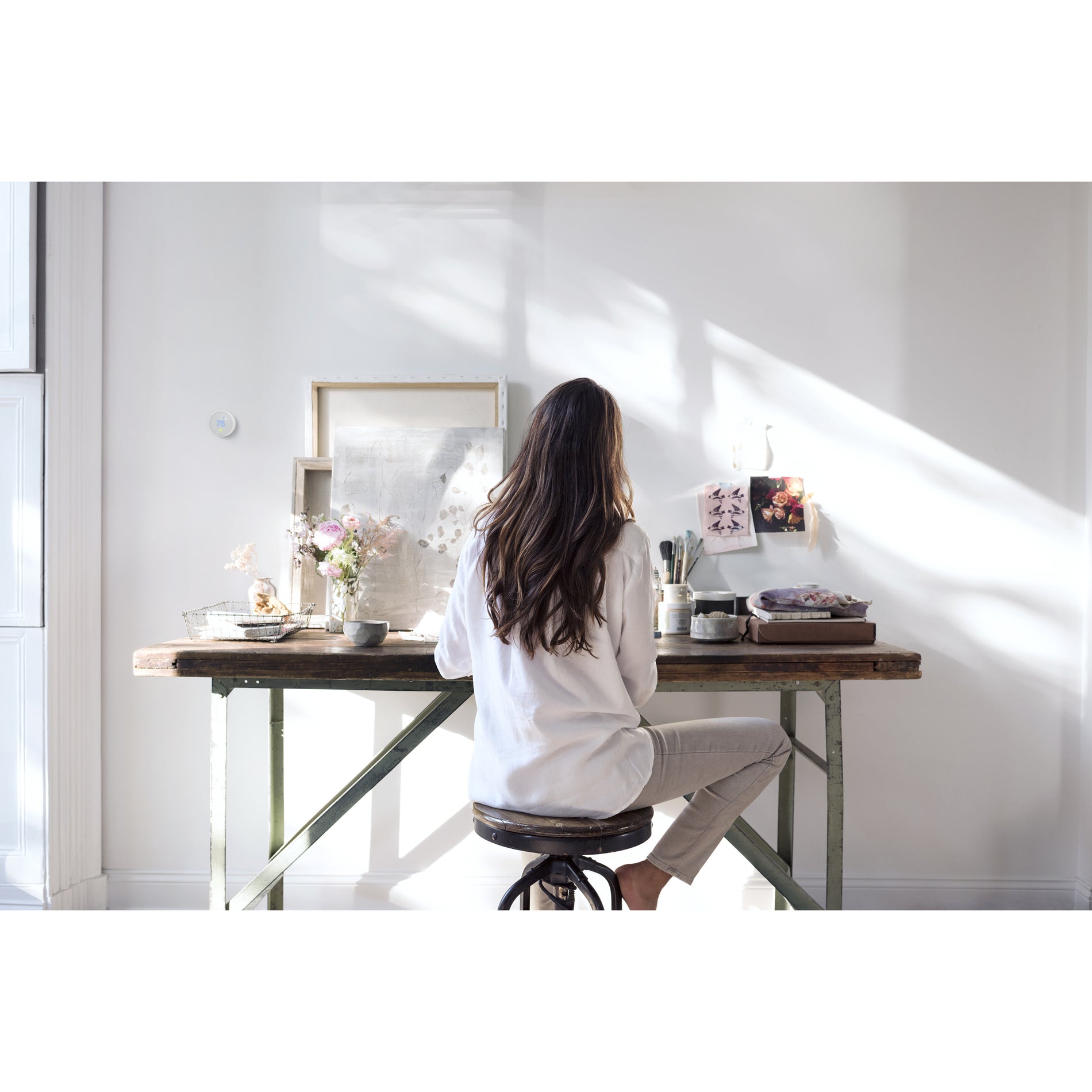 Person working at desk with Nest Thermostat E visible in background-alternate-image6