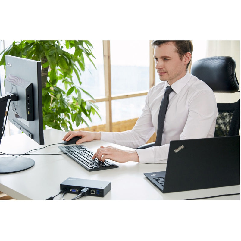 Professional using Lenovo Essential USB Mouse in an office setting with desktop computer