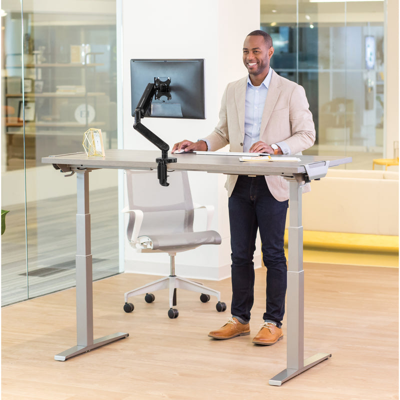 Professional engaged in work at Fellowes Levado height-adjustable desk with modern office background