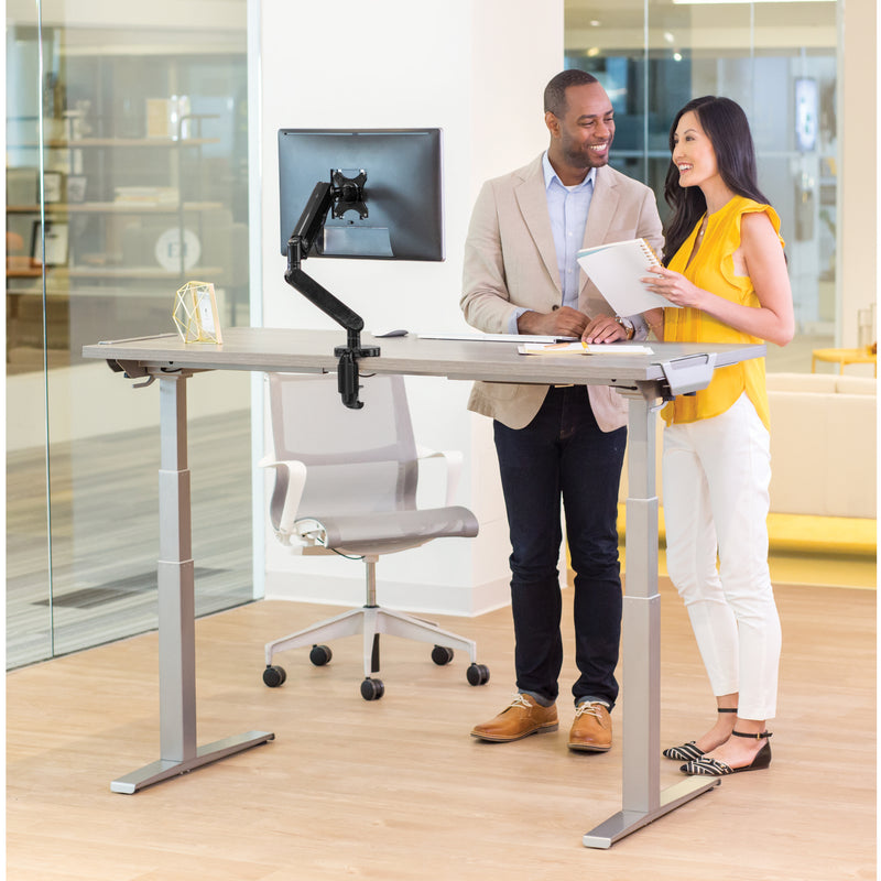 Two professionals collaborating at a Fellowes Levado height-adjustable desk with monitor arm