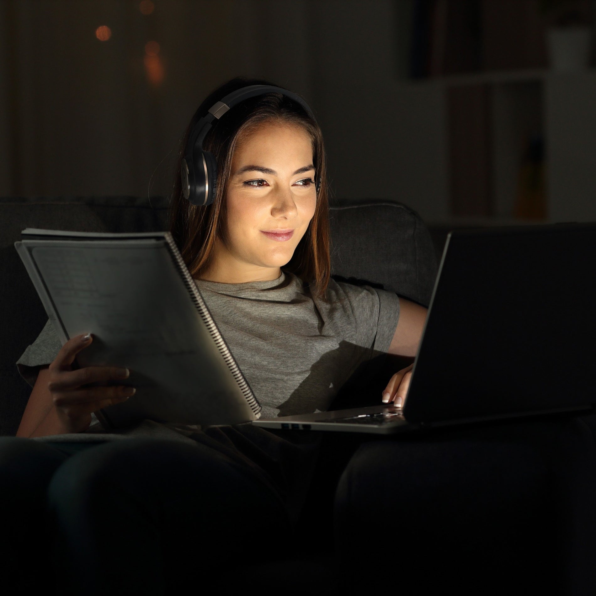 Person studying at night wearing Morpheus 360 headphones with laptop and notebook-alternate-image7