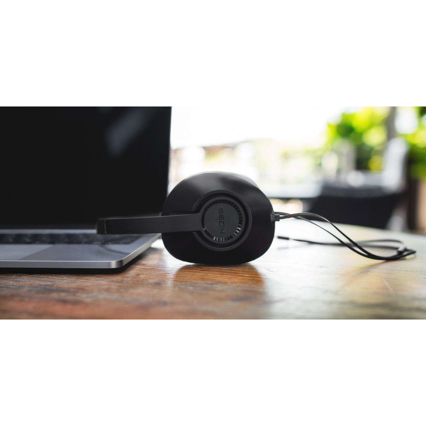 Koss UR23i headphones placed next to laptop on wooden desk-alternate-image5