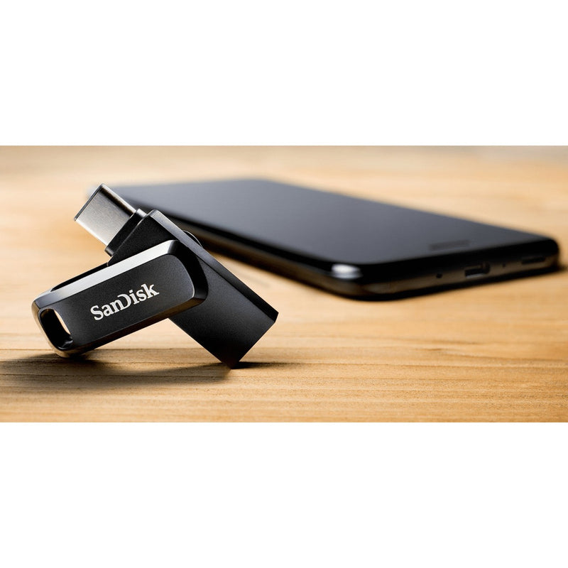 SanDisk Ultra Dual Drive Go next to smartphone on wooden surface