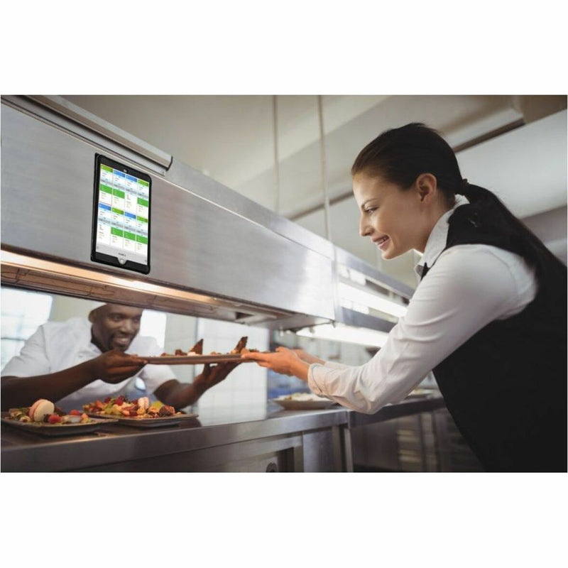 Restaurant kitchen scene showing mounted iPad being used for order management