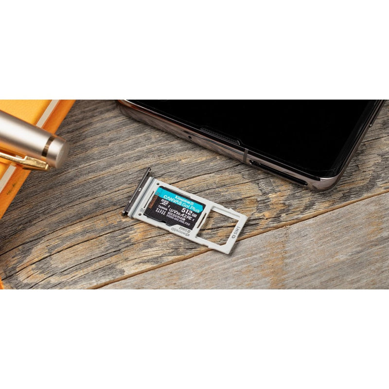 Kingston microSD card next to smartphone SIM tray on wooden surface