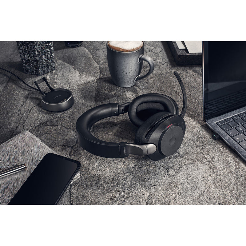 Jabra Evolve2 85 headset with charging stand and connected devices on desk