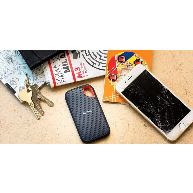 Lifestyle shot of SanDisk Extreme Portable SSD with travel essentials and damaged phone