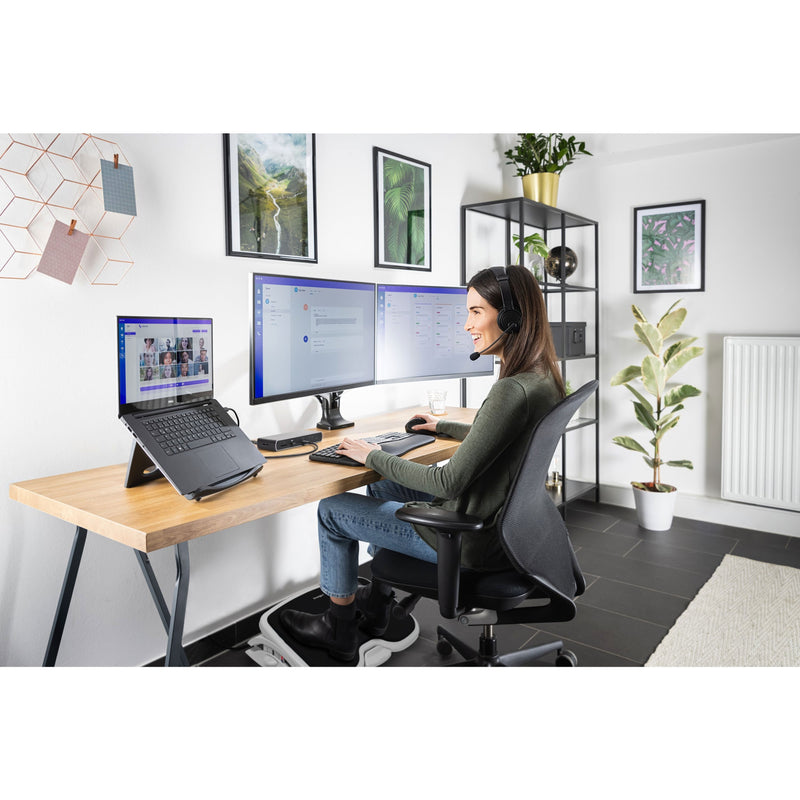 Woman using Kensington headset in modern home office setup with multiple monitors