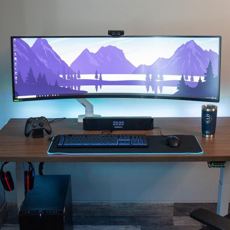 Complete gaming setup featuring ultra-wide monitor mounted on Ergotron HX arm with RGB keyboard and gaming controller