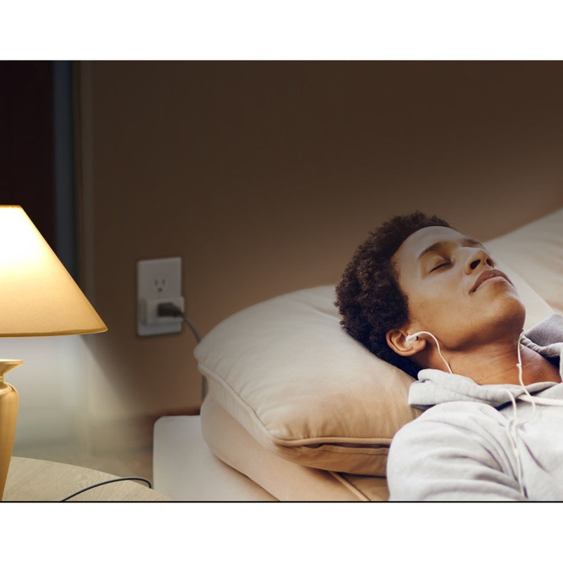 Person relaxing with earphones while smart plug controls bedside lamp