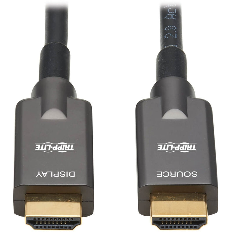 Close-up of gold-plated HDMI connectors on Tripp Lite P568FA-10M fiber optic cable showing source and display labels