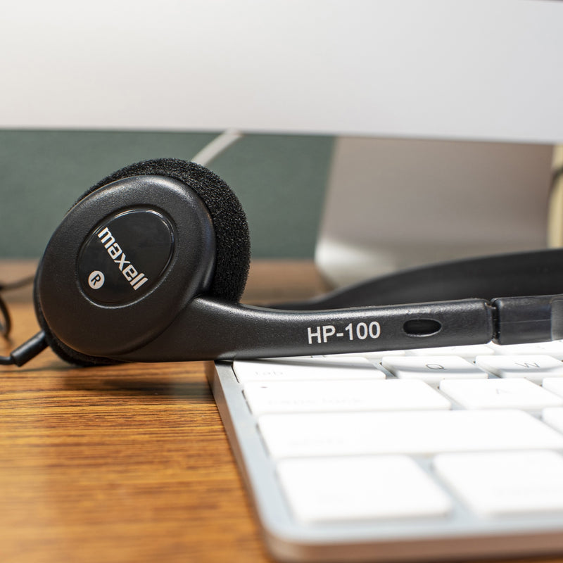 Maxell HP100 headset positioned next to keyboard showing desktop compatibility