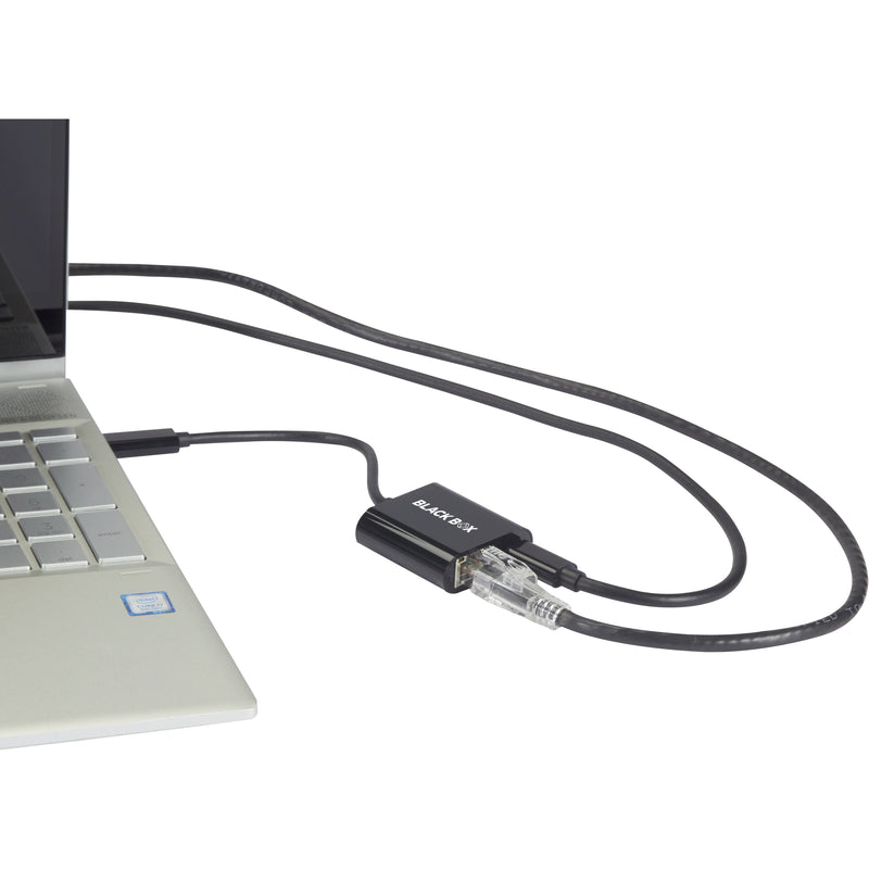 Close-up view of Black Box USB-C to Ethernet adapter connected to a laptop with Ethernet cable