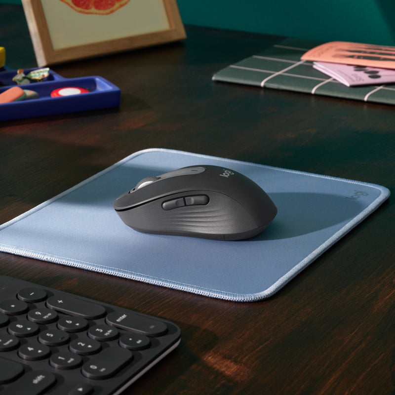 Logitech M650 mouse on desk with keyboard in professional workspace setting