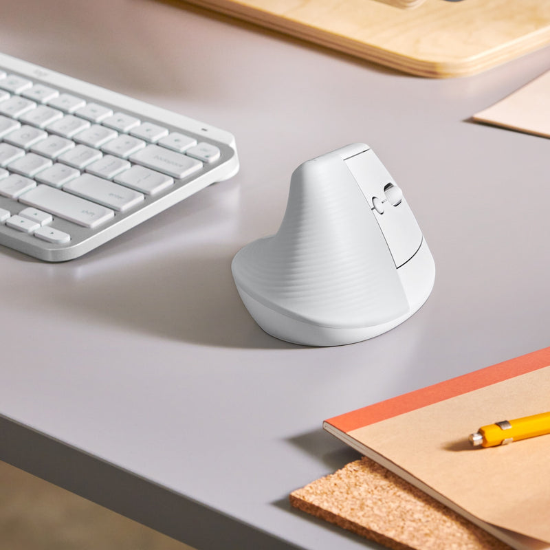 Logitech Lift mouse on desk next to white keyboard in modern workspace setting